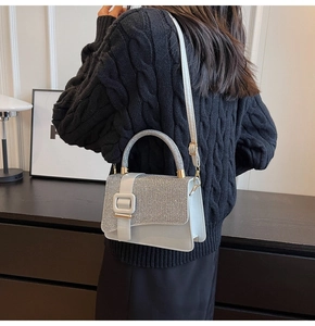 Detail of white leather shoulder bag with sparkling silver rhinestone flap and big buckle