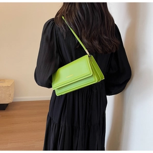 Detail of a bright green rectangular leather shoulder bag worn on a black dress