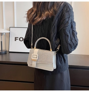 Detail of elegant silver rhinestone handbag with white leather and square buckle