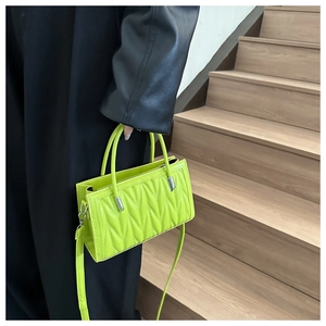 Close-up of neon green quilted handbag with V-shaped stitching and dual handles