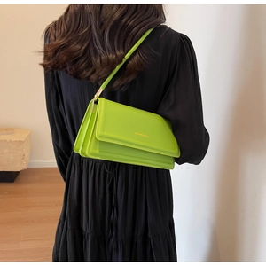 Detail of neon green leather underarm bag featuring gold FASHION BAG text and flap closure