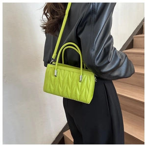Detail view of fluorescent green crossbody bag with V-shaped quilted pleats and handle