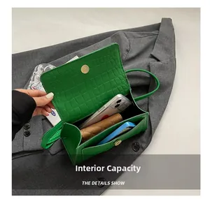 Macro shot of green crocodile pattern bag interior showing main compartment and front pocket