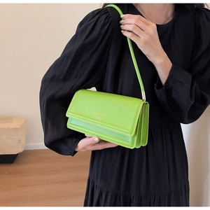 Close-up of neon green leather shoulder bag with gold embossed logo on a model