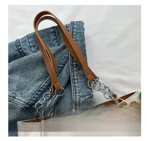 Detail of light beige tote bag with brown leather straps and silver metal chains
