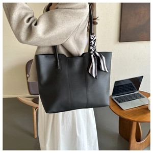 Detail of black PU leather tote bag featuring a striped silk ribbon on the shoulder handle