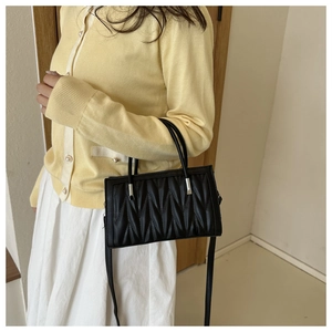 Close-up of black quilted PU leather crossbody bag with V-pattern and metallic handle