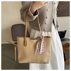 Detail of soft beige PU leather tote bag with a checkered ribbon on the handle