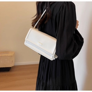 Back view of a model wearing a white matte leather shoulder bag with FASHION BAGS print