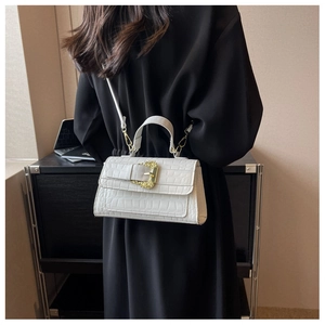 Detail of white crocodile texture handbag with golden embossed baroque buckle decoration