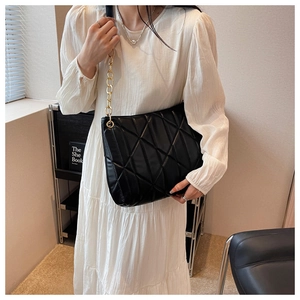 Detailed view of black quilted shoulder bag with gold chain strap and diamond stitching