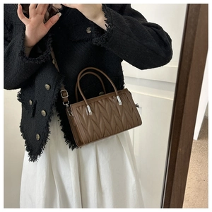 Brown pleated texture small square handbag shown in a lifestyle model selfie view