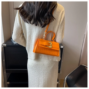 Side view of orange croc-effect crossbody bag with vintage golden baroque buckle