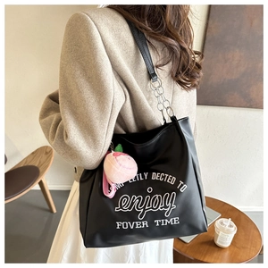 Detail of black PU leather tote bag featuring white letter embroidery and a metal chain strap