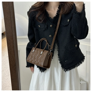 Brown quilted crossbody bag detail showing vertical pleats and silver hardware accents