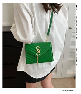 Detail of green V-quilted crossbody bag with golden S logo and elegant metal tassel