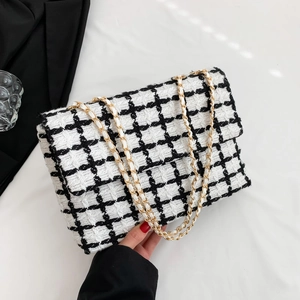 Sac bandoulière classique en tweed à carreaux noir et blanc avec chaîne dorée sur fond blanc