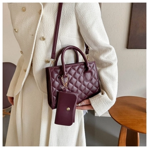 Detail of burgundy quilted crossbody bag with small coin purse and golden hardware