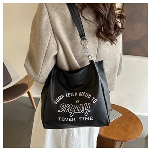 Detailed view of black tote bag with white lettering print and metal chain strap
