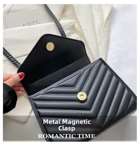 Detail of black chevron quilted flap bag featuring a shiny gold magnetic snap closure