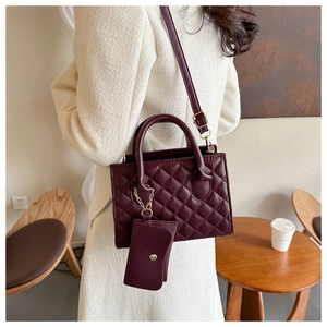 Detail of wine red quilted handbag with matching detachable pouch and gold hardware