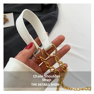 Detail of white leather shoulder strap with bold gold metal chain and fine stitching