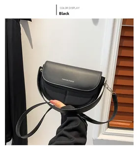 Dettaglio della borsa a sella nera opaca con logo argento e sottile tracolla in pelle