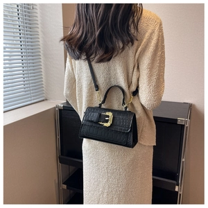 Detail of black faux crocodile leather bag with golden baroque buckle and strap