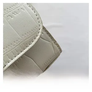Close-up of cream faux crocodile texture and neat stitching on a women crossbody bag