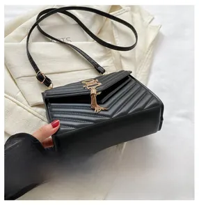 Detail of black quilted shoulder bag featuring V-shaped stitching and golden tassel charm