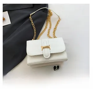 White croc-effect crossbody bag with gold H-clasp and chain strap shown with smartphone