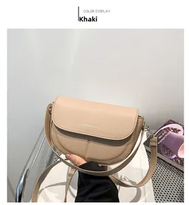 Vista laterale di una borsa a sella kaki semicircolare tenuta da una modella in studio