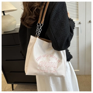 Detail of white PU leather tote with enjoy pink embroidery and metal chain strap
