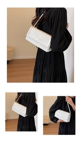 Detailed view of a white leather crossbody bag with fashion gold lettering and pleated sides