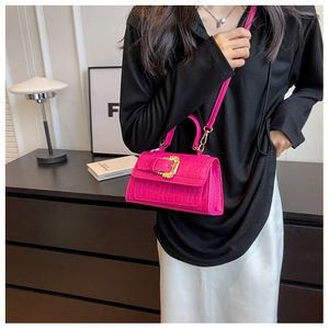 Detail of fuchsia crocodile embossed leather handbag with a gold baroque style buckle