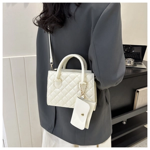Close-up of white quilted crossbody bag with a mini coin purse and golden chain detail