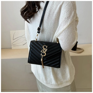 Detailed back view of model wearing a black V-quilted crossbody bag with tassel