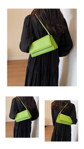 Detailed back view of a neon green rectangular shoulder bag on a black dress model