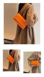Close-up of bright orange faux leather shoulder bag with golden FASHION & BAGS lettering