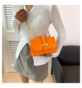Detail of orange crocodile pattern crossbody bag with golden H clasp and chain strap