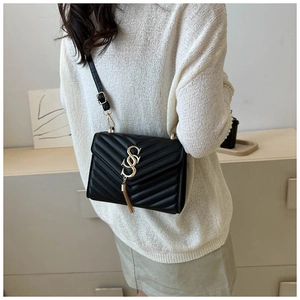Detail of black quilted leather bag with gold metal hardware and stylish tassel charm