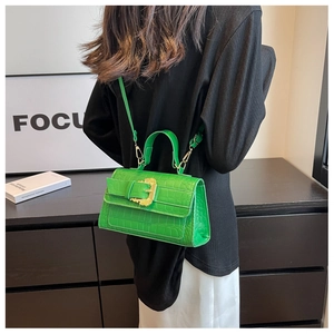 Detail of green crocodile texture handbag with gold baroque buckle and shoulder strap
