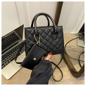 Close-up of black quilted handbag with matching small coin purse and golden hardware