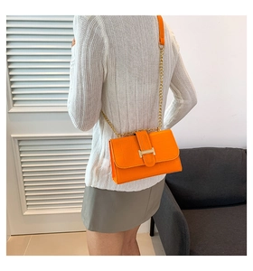 Detail of orange crocodile pattern crossbody bag with gold chain and metal H buckle