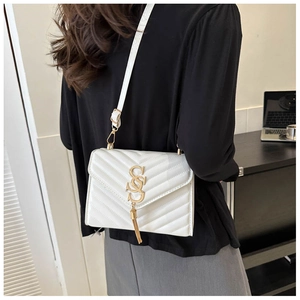 Detail of white quilted crossbody bag with gold metal SS logo and stylish tassel charm