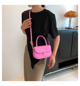 Dettaglio borsa rosa vivace motivo coccodrillo con fibbia dorata e tracolla regolabile