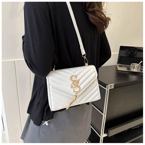 Detail of white quilted crossbody bag with golden V-stitching and S-logo tassel