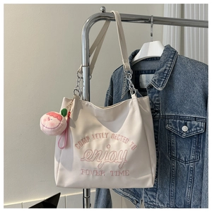 Detail of white tote bag with pink letter embroidery and metal chain strap
