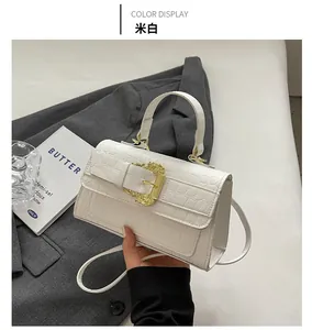 Detail of off-white crocodile embossed handbag with ornate golden baroque buckle