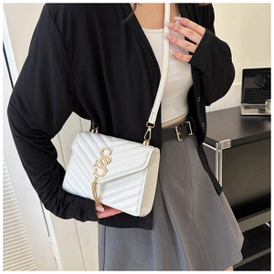 Close-up of white quilted PU leather crossbody bag with gold V-pattern and tassel detail